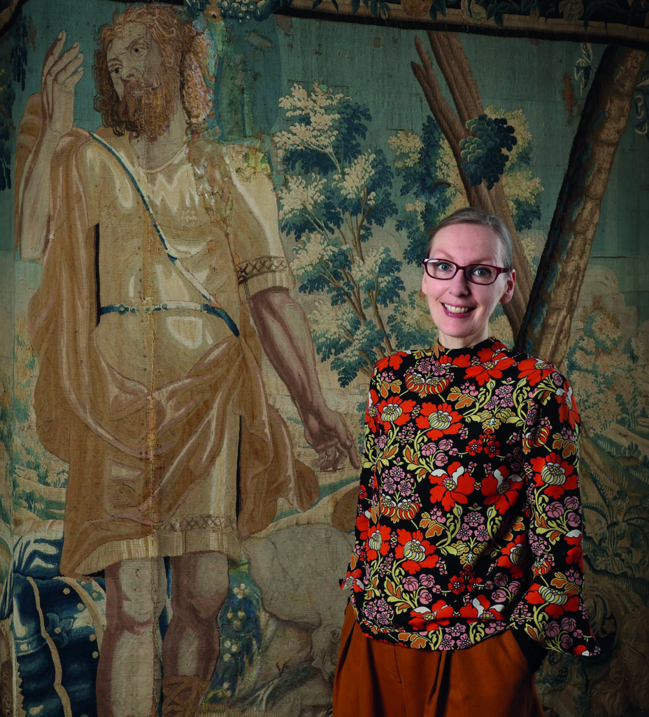 Dr Kathy Haslam FSA in front of the tapestry showing Samson and the Philistines
