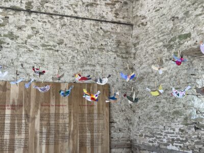 Art installation of decorated bird hanging in barn