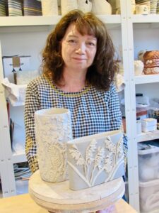 ceramicist alsion standing in front of two vases she has made
