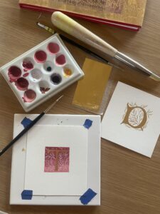 flat lay of illuminated letter, paints and pen