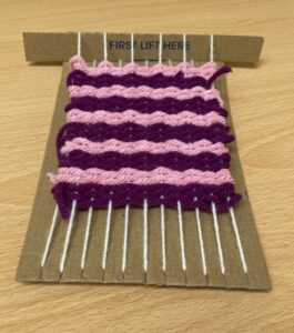 cardboard loom with purple woven sample